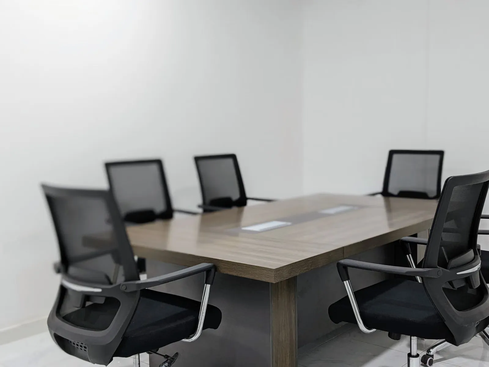 Sala de reuniones con mesa y sillas preparada para una sesión.