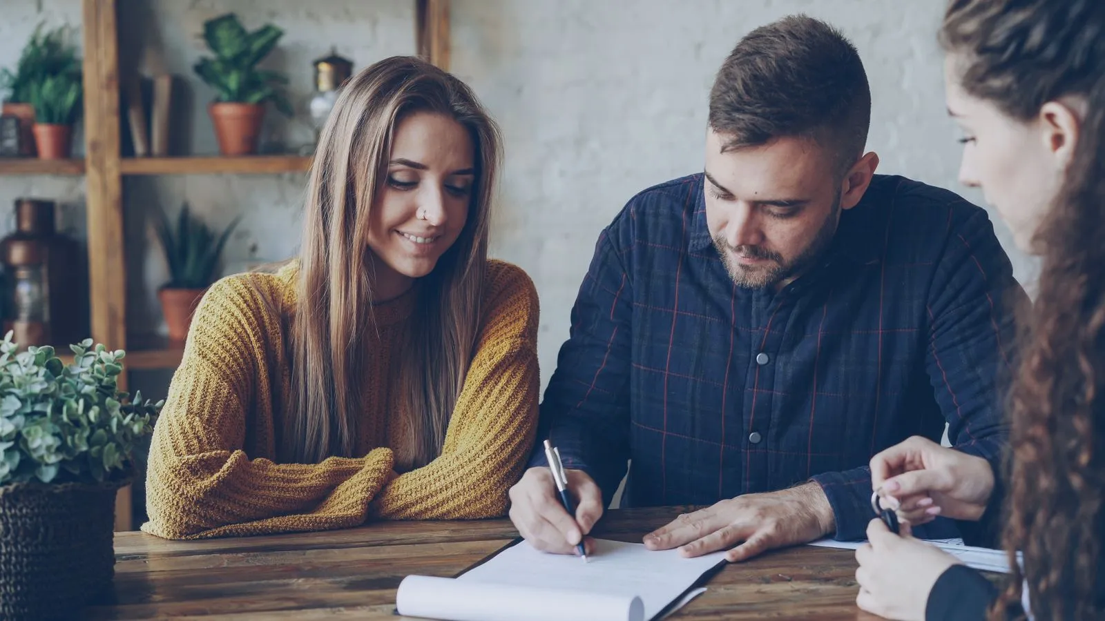 Personas que revisan y firman documentos en una mesa de oficina.
