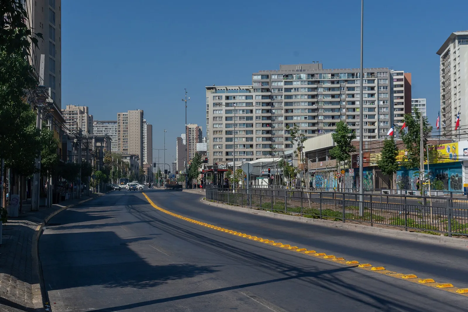 Avenida Independencia, en la comuna de Independencia, Santiago: calzada con línea amarilla, locales comerciales y edificios de departamentos al fondo.