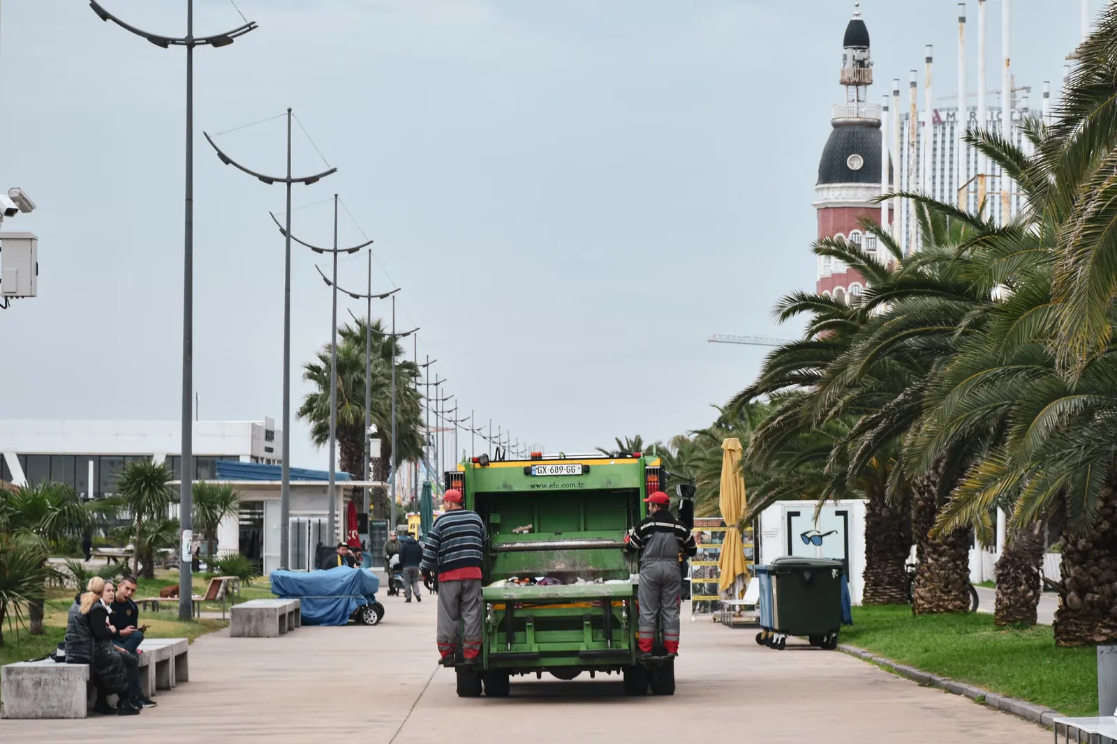 Camión de recolección de residuos junto a una avenida arbolada.
