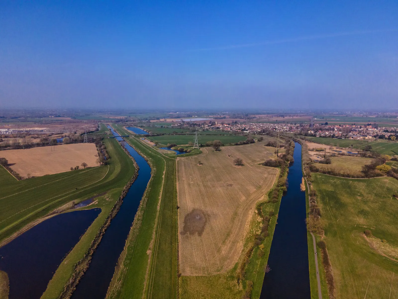 Vista aérea de canales y estanques de agua entre campos agrícolas y una localidad rural.