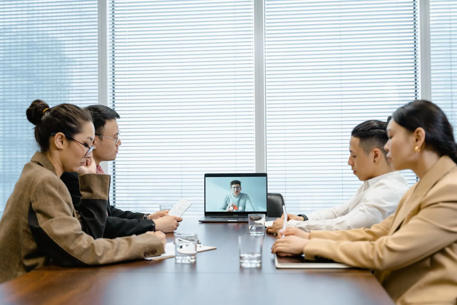 Profesionales participan en una videorreunión desde una mesa de trabajo.