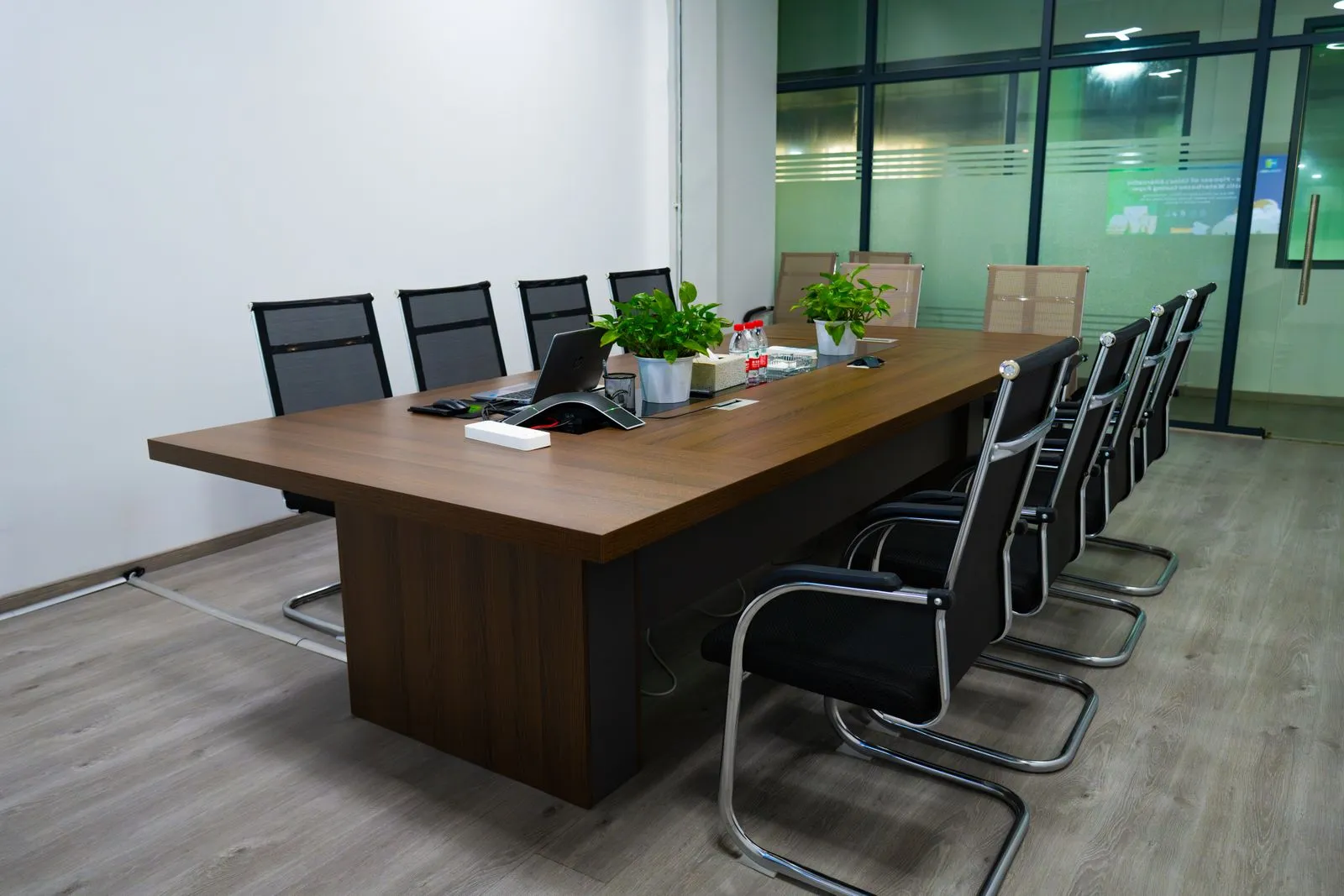 Sala de reuniones vacía con mesa de madera y sillas dispuestas alrededor.