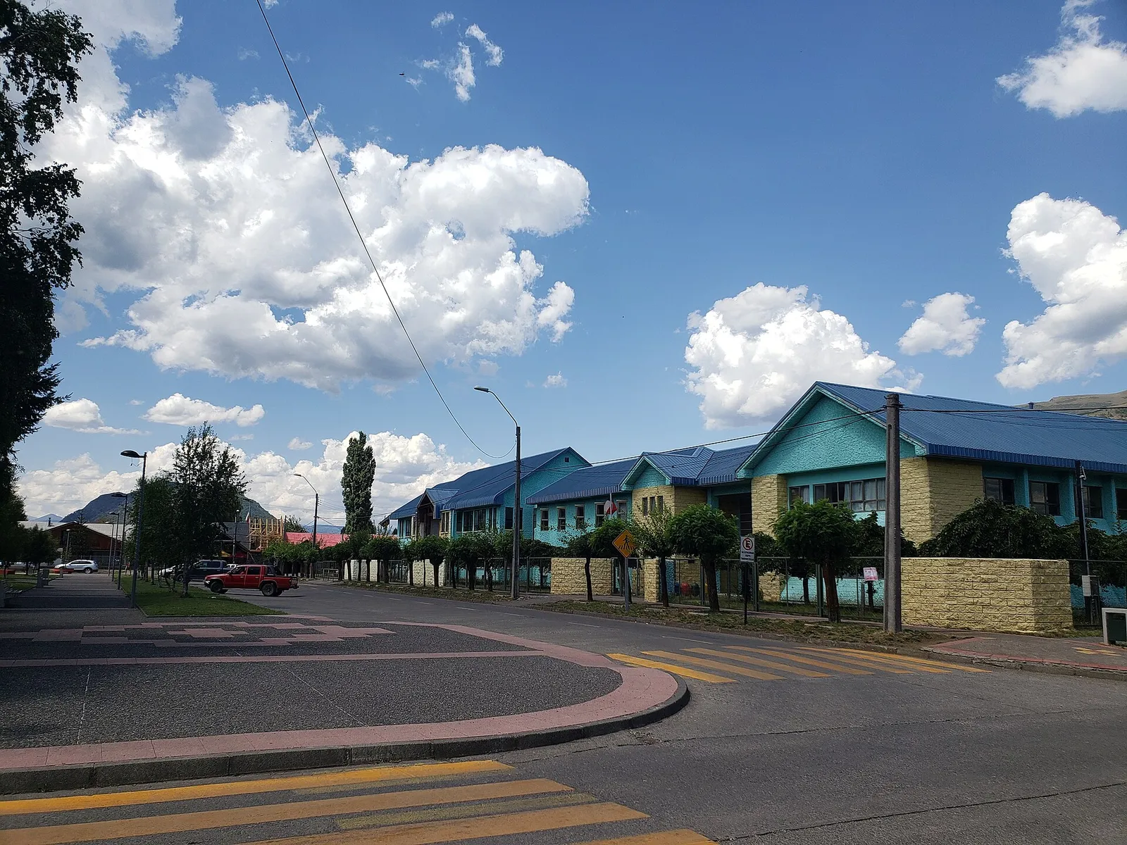 Escuela Fronteriza de Lonquimay, Región de La Araucanía: pabellones de techo azul y muros celestes junto a una calle, bajo un cielo con nubes.