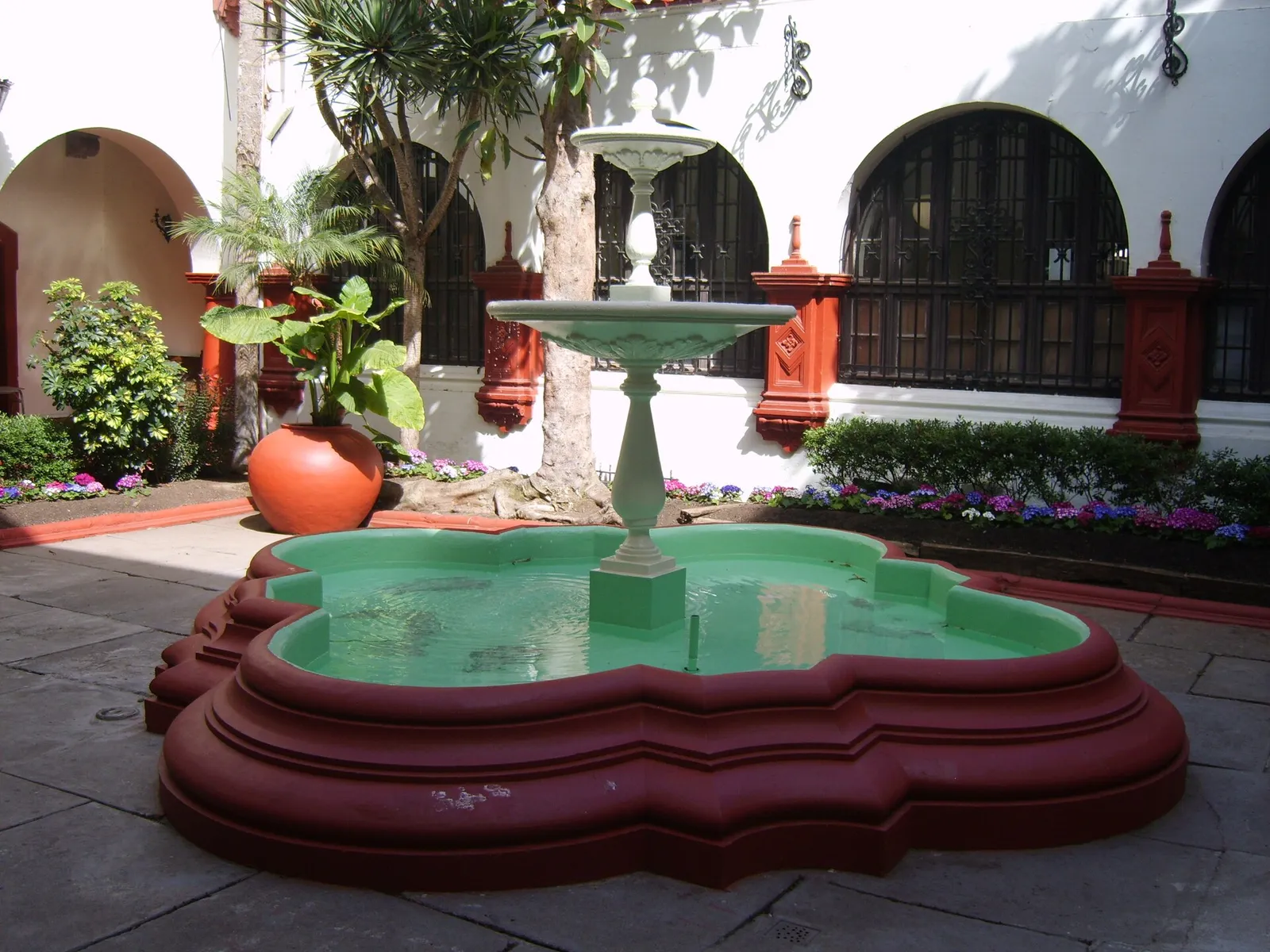 Pileta en el patio interior de la Municipalidad de La Serena, rodeada de plantas y arcos con rejas de hierro.