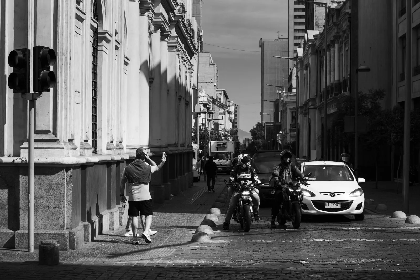 Fotografía en blanco y negro de una calle de Santiago con peatones y vehículos.