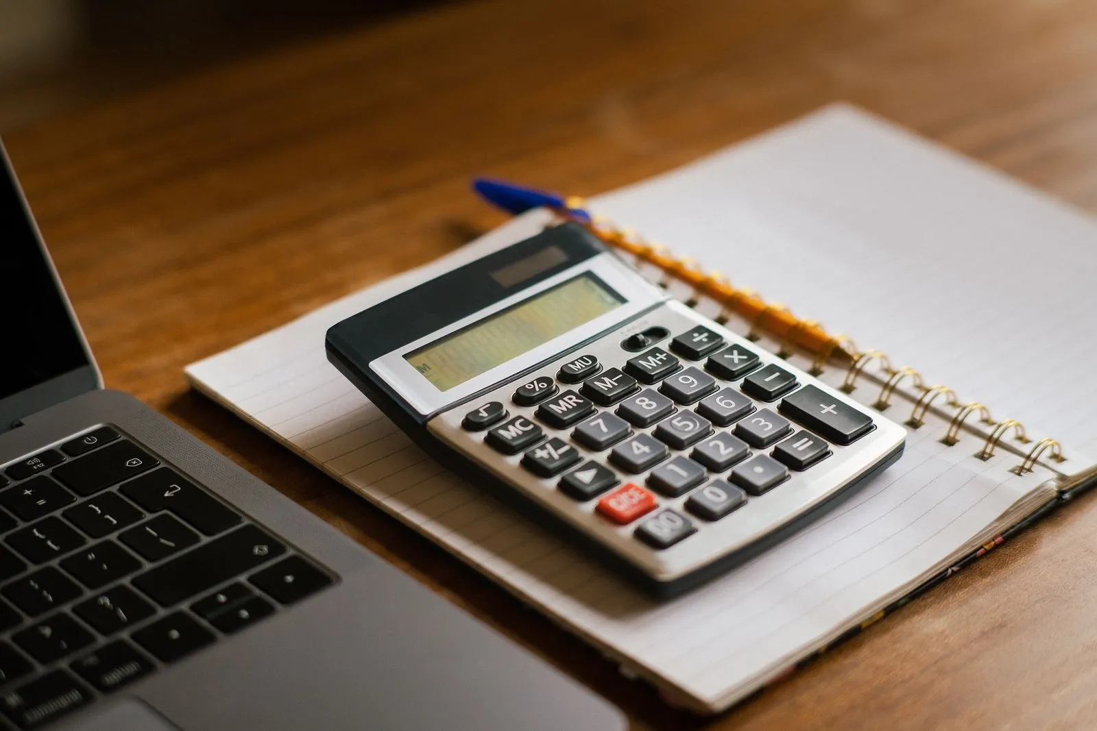 Calculadora, anteojos y papeles sobre un escritorio de contabilidad.