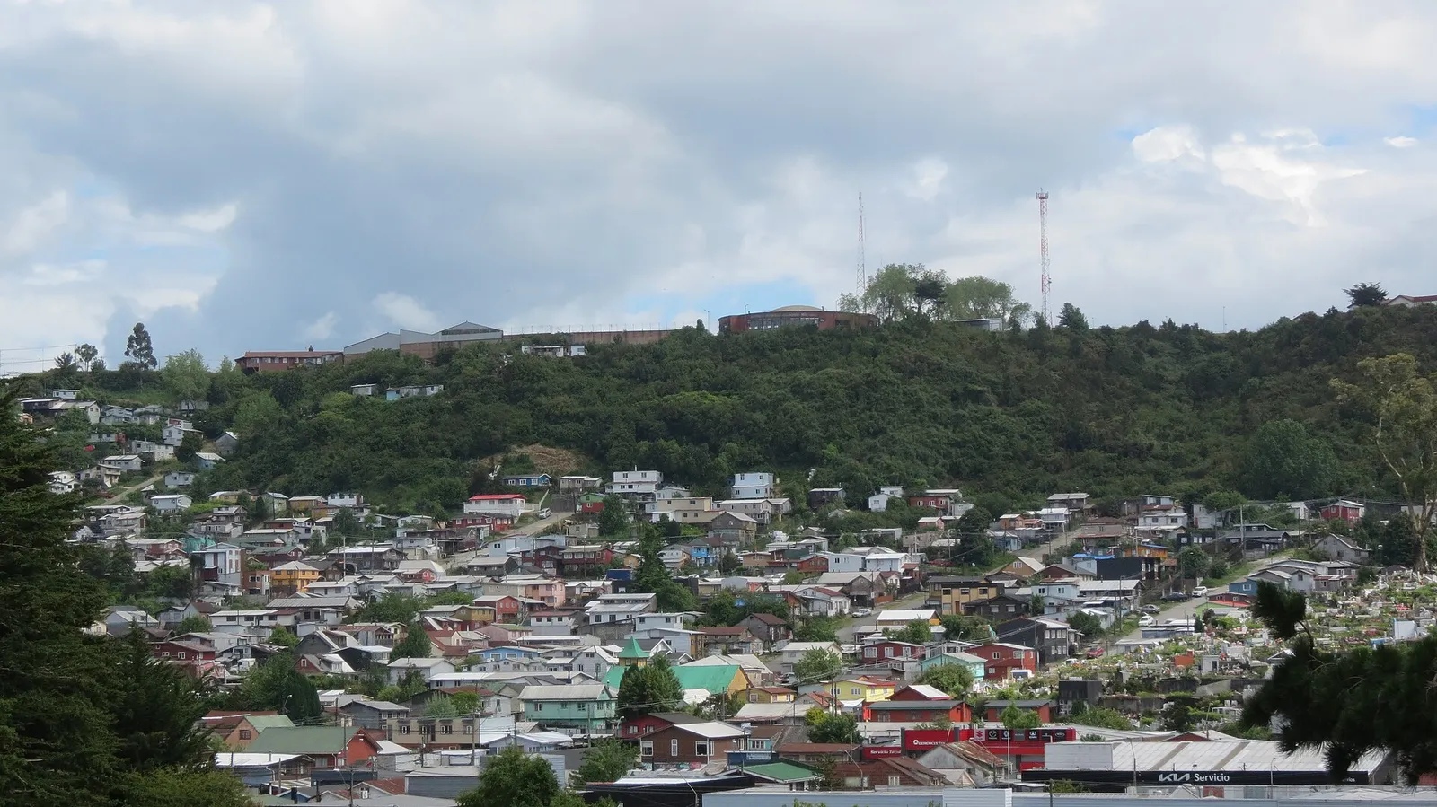 Barrio Modelo de Puerto Montt visto desde el cerro San Javier: casas de colores en la ladera y vegetación en lo alto del cerro.