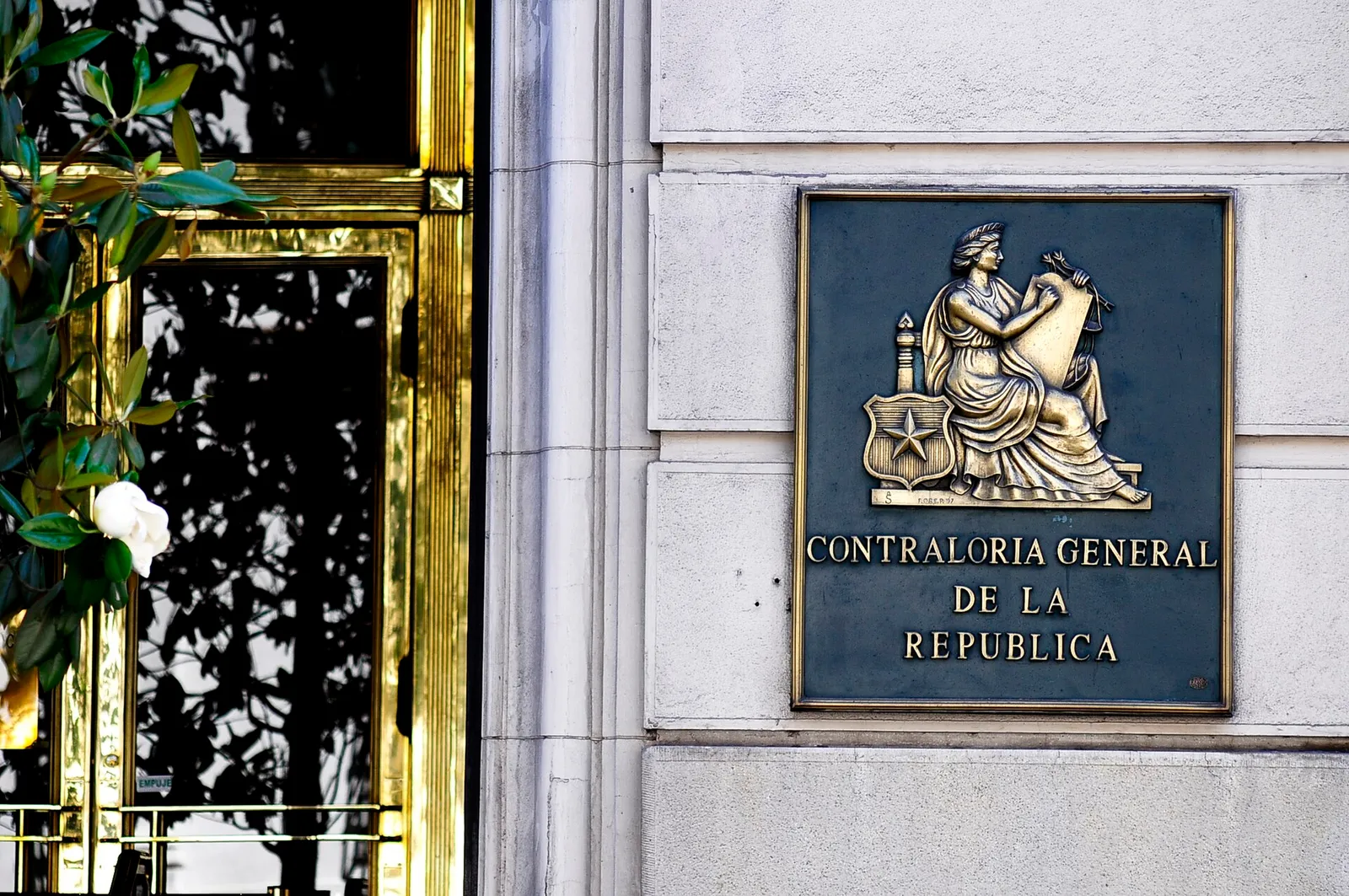Placa de la Contraloría General de la República en la fachada de su edificio de calle Teatinos, en Santiago, junto a una reja de bronce.